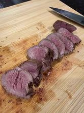 Sliced beef on a wooden cutting board with a knife